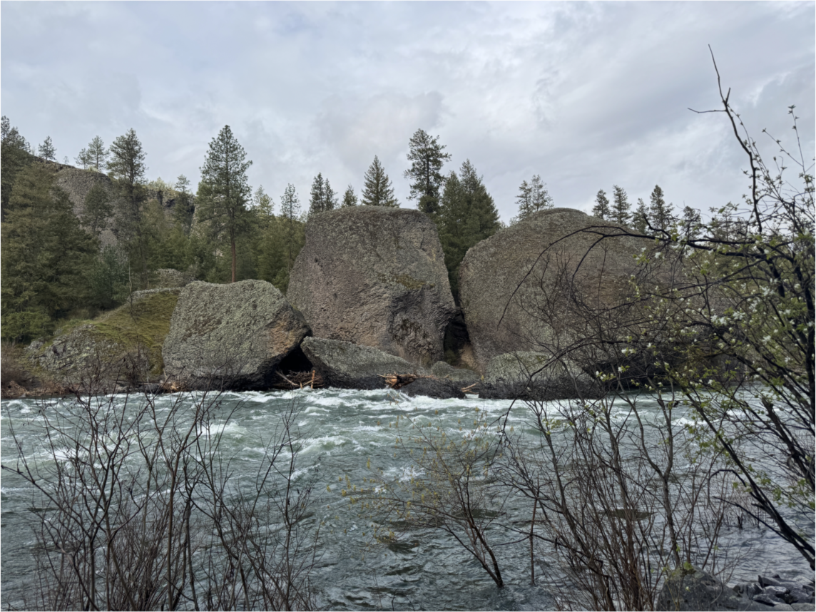 Grey rocks stand tall next to the Spokane River